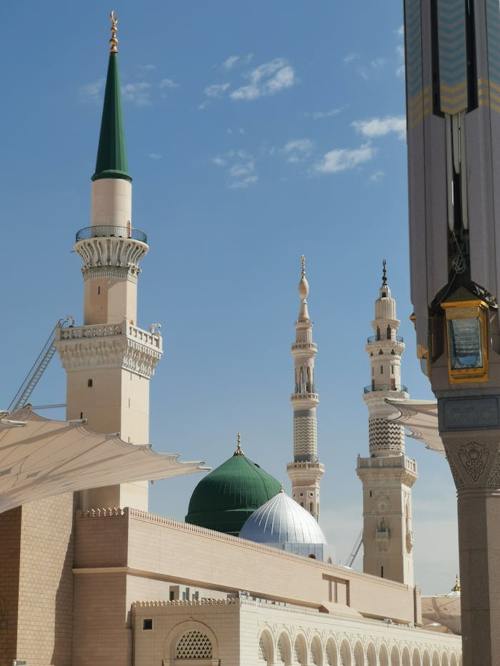 An iconic capture of the minarets and dome of Al-Masjid an-Nabawi in Medina under a clear blue sky.