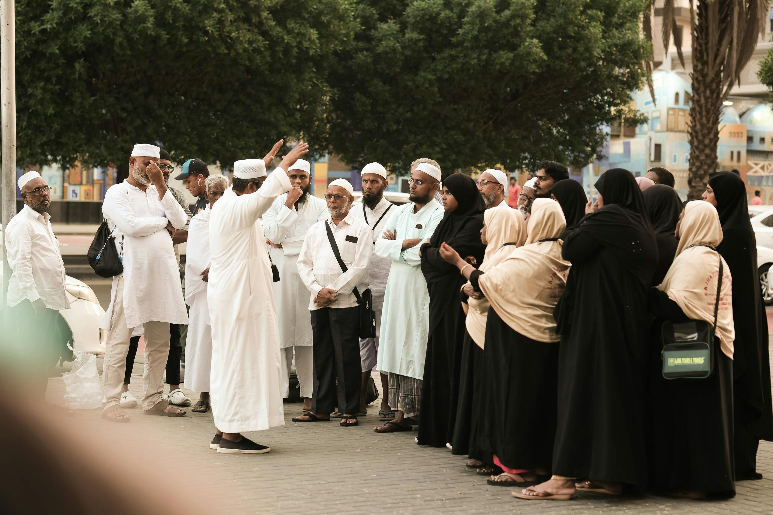 pexels photo 30636370 30636370 A group of pilgrims in traditional attire gather on a street in Saudi Arabia, engaging in discussion.